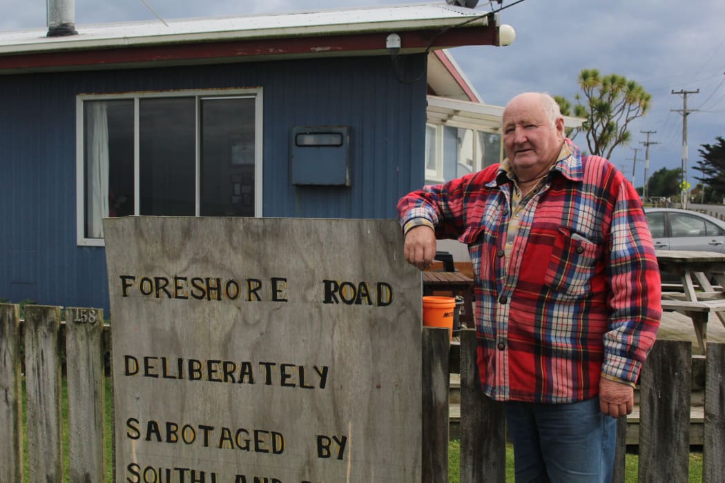 Kevin Mulqueen leans against a sign he attached to the fence of his Colac Bay home.