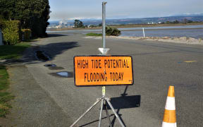 A sign warns Nelson residents of potential flooding due to high tide.