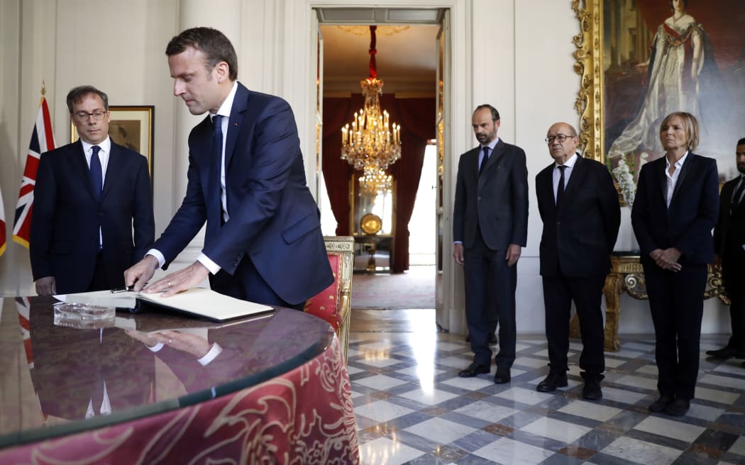 French President Emmanuel Macron signs a book of condolences at the British Embassy, flanked by English ambassador Edward Llewellyn, French Prime Minister Edouard Philippe, Foreign Affairs Minister Jean-Yves Le Drian and Minister for European Affairs Marielle de Sarnez.