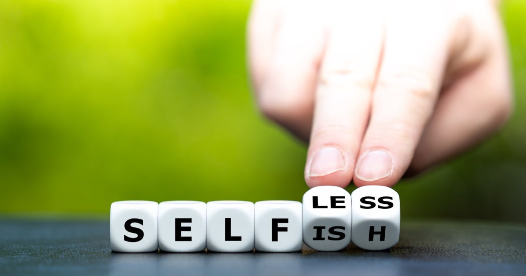Hand turns dice and changes the word "selfish" to "selfless"No caption.