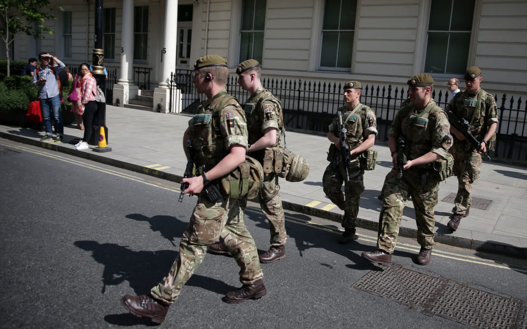 British Army soldiers are led by a police officer into Buckingham Palace in central London.