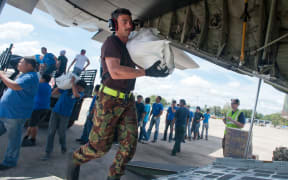 Leading Aircraftman Daniel Stone loads the RNZAF’s C-130 with 41kg sack of rice and tinned food for typhoon survivors.