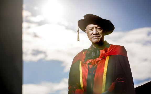 Te Piere smiles at the camera. He wears a graduate's robes and hat.