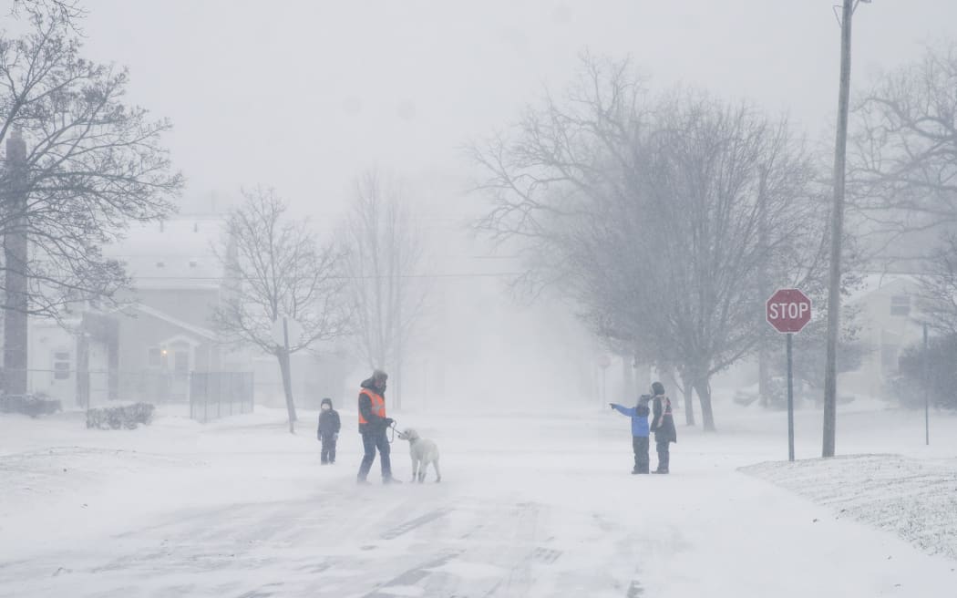 A family walks and runs during a winter snow storm affecting most of the USA, in Flint, MI on December 23, 2022.