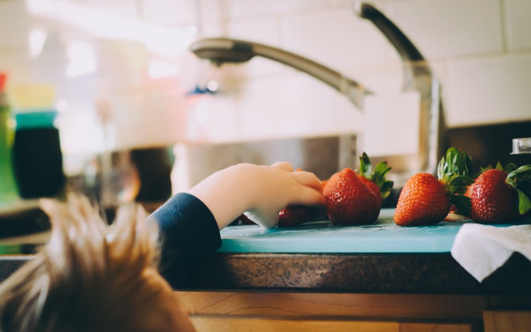child reaching for strawberries
