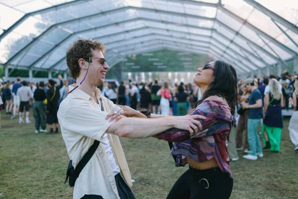 A man and woman holding arms and dancing outdoors at a gathering.