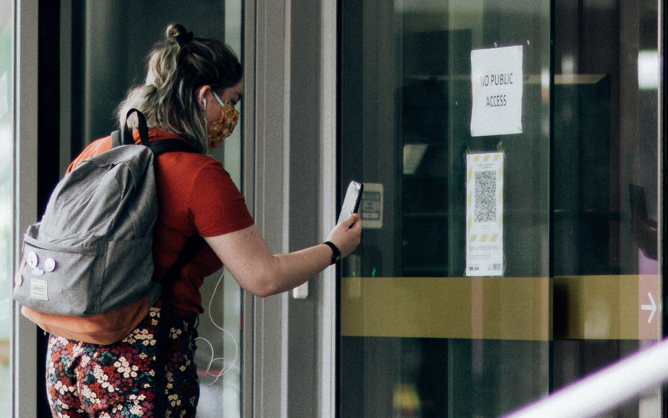 A woman using the Covid Tracer app at a QR code in the window of a business during level 2 in Wellington on15 February 2021