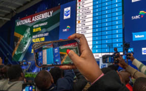 Guests and delegates use their phone at the formal announcement Sunday, June 2, 2024 of the results in South Africa's general elections at the National Results Operations Center in Johannesburg, South Africa. Humbled by a stinging election result, South Africa's African National Congress was talking to everyone in an effort to form a stable coalition government for Africa's most advanced economy after it lost its 30-year majority. (AP Photo/Jerome Delay)