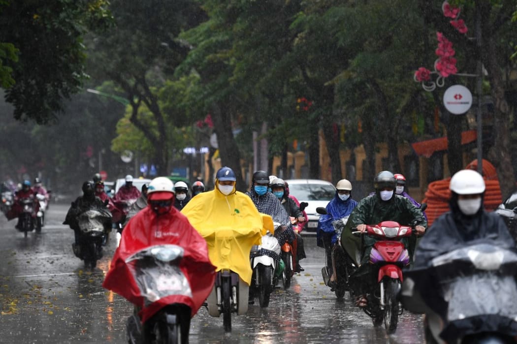 Motorists wearing face masks ride amid a downpour in Hanoi as Vietnam eased its nationwide social isolation effort to prevent the spread of the COVID-19.
