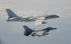 This handout photo taken and released on February 10, 2020 by Taiwan's Defence Ministry shows a Taiwanese F-16 fighter jet flying next to a Chinese H-6 bomber (top) in Taiwan's airspace.