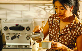 An image from Celeste Wong's book, Coffee Creations: 90 delicious recipes for the perfect cup. Celeste Wong pours milk into her coffee cup to make a flat white.