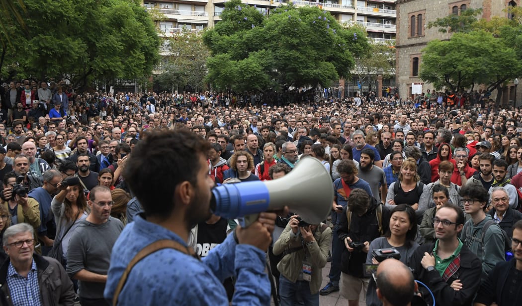 People listen to a referendum volunteer giving instructions on how to behave in case of a police intervention outside a polling station at the Industry School of Barcelona, on October 1, 2017,