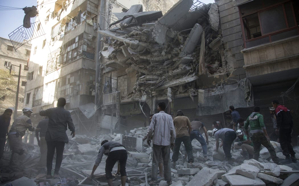 Syrian civilians and rescuers gather at site of government forces air strikes in the rebel held neighbourhood of Al-Shaar in Aleppo.