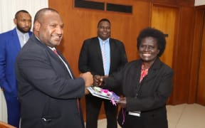 Papua New Guinea's Prime Minister James Marape receives a final report into the Bougainville Referendum from Ruby Miringka of the Bougainville Referendum Commission.