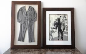Philip O'Neill's childhood suit, framed, next to a picture of him as a child wearing the suit walking hand in hand with his suit-wearing father.