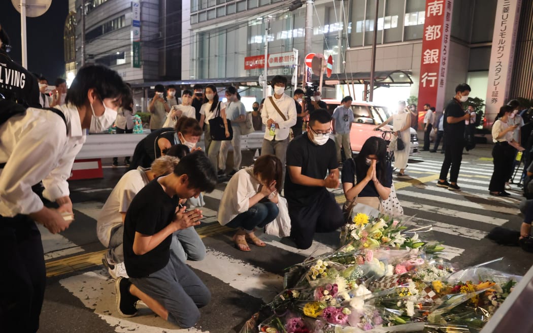 People lay a bouquet of flowers at the site where former Japanese Prime Minister Shinzo Abe was shot to death near Yamato Saidaiji Station in Nara Prefecture on 8 July 2022.