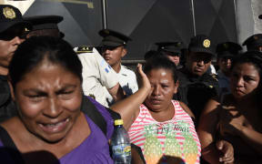 Relatives cry outside the children's shelter Virgen de la Asuncion, guarded by police, after a fire at the facility killed at least 19 people, in San Jose Pinula, 10 km east of Guatemala City, on 8 March.