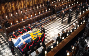 Queen Elizabeth II (L) watches as pallbearers carry the coffin of Britain's Prince Philip, Duke of Edinburgh during his funeral inside St George's Chapel in Windsor Castle in Windsor, west of London, on April 17, 2021.