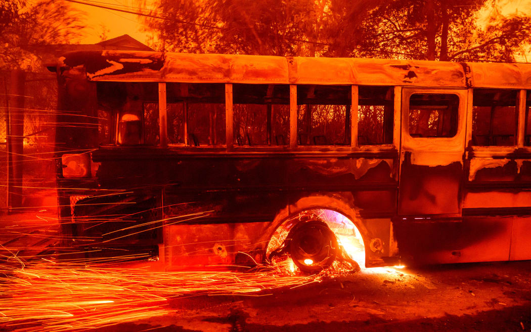 Embers fly off a burning bus at Aveson School of Leaders elementary school during the Eaton fire in the Altadena area of Los Angeles County, California on January 8, 2025. (Photo by JOSH EDELSON / AFP)