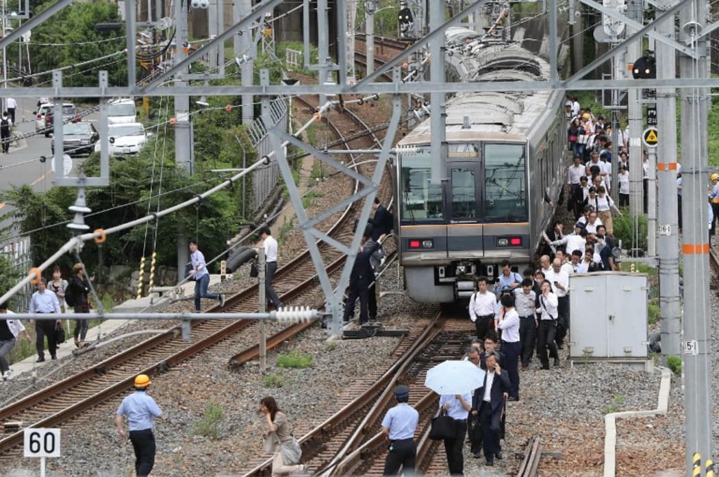 Passengers from a train walk along railroad tracks following an earthquake in Osaka on June 18, 2018.
