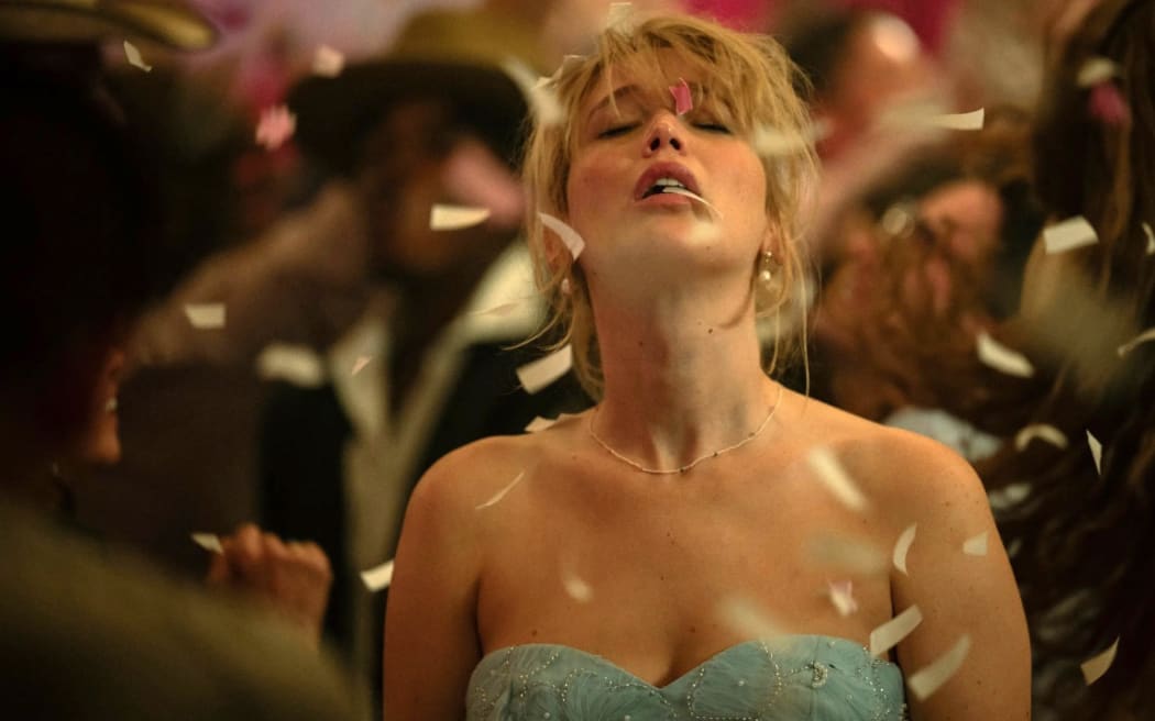 Jennifer Lawrence, in a blue strapless dress, looks up with eyes closed as confetti falls around her.
