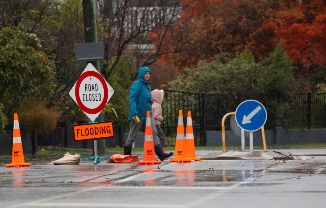 A woman and her child walk past a road closure due to flooding sign boardÂ in Christchurch, NewÂ Zealand on May 30, 2021.