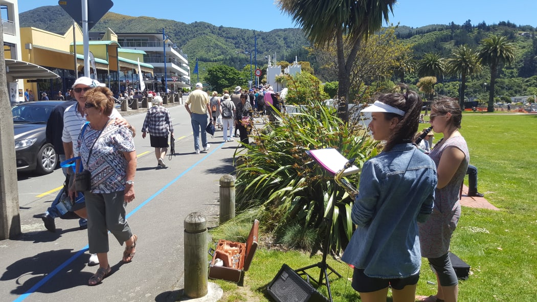 A young busker keeps the line of passengers entertained with jazz in downtown Picton, while they wait to catch a bus back to the ship in nearby Shakespeare Bay.