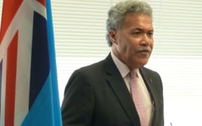Tuvalu Prime Minister Enele Sopoaga and the flag of Tuvalu.