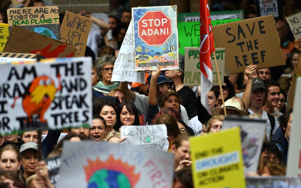 This picture taken on March 15, 2019 shows students raising placards during a protest highlighting inadequate progress to address climate change, in Sydney.