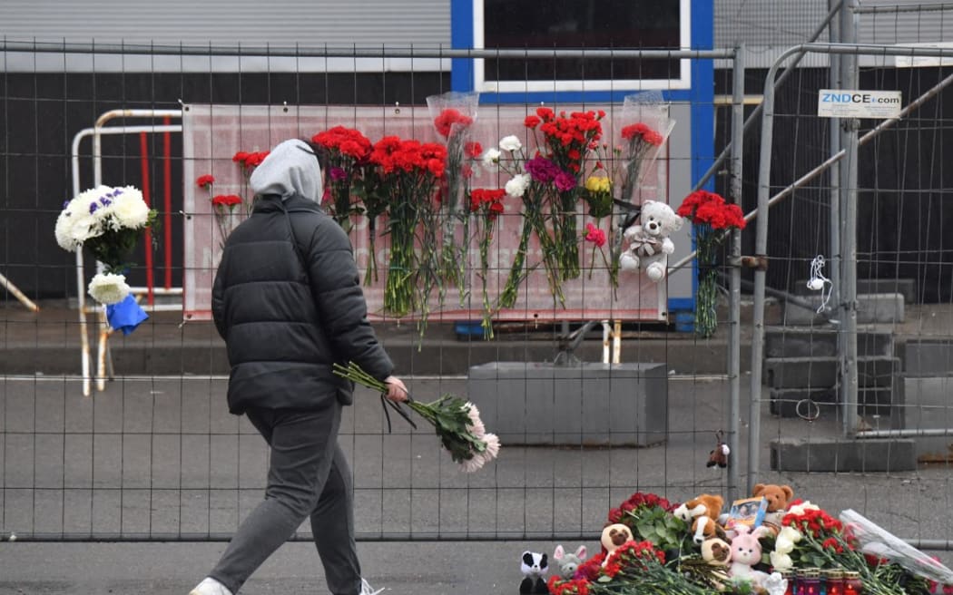 A woman lays flowers at a makeshift memorial in front of the Crocus City Hall, a day after a gun attack in Krasnogorsk, outside Moscow, on March 23, 2024. Gunmen who opened fire at a Moscow concert hall killed more than 90 people and wounded many others while sparking an inferno, authorities said Saturday, with the Islamic State group claiming responsibility. (Photo by Olga MALTSEVA / AFP)