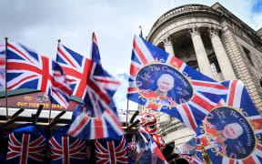 Union Jack flags and flags picturing Britain's King Charles III flap in the air as they are displayed at a street souvenirs vendor stall, in Trafalgar Square, central London, on May 5, 2023, ahead of the coronation weekend. - The country prepares for the coronation of Britain's King Charles III and his wife Britain's Camilla, Queen Consort on May 6, 2023.