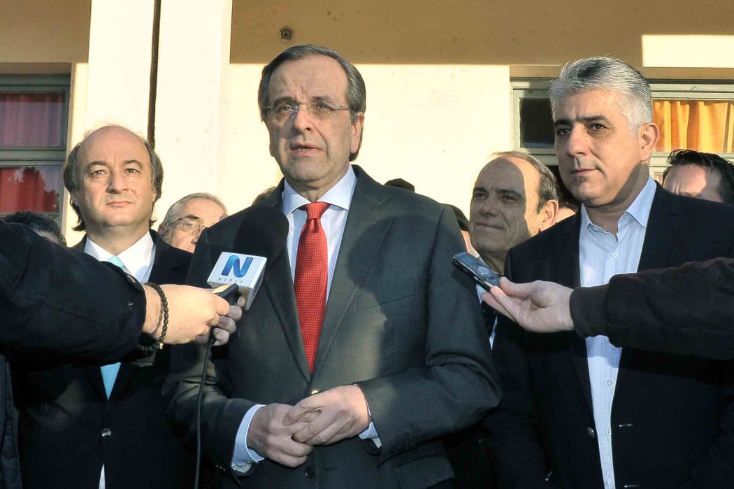 Outgoing PM Antonis Samaras (C) talks to journalists after voting at a polling station in Pylos in January 2015.