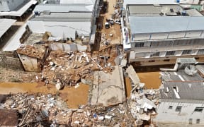 Aerial view showing streets of the commercial district of Uba, in Minas Gerais State, Brazil, on February 25, 2026, where a bridge and several buildings collapsed after the Uba River overflowed due to heavy rains. Despair hung over two cities in southeastern Brazil on February 25 as rescuers and residents searched for 27 people missing after torrential rains unleashed flooding and landslides that killed at least 40. (Photo by Pablo PORCIUNCULA / AFP)