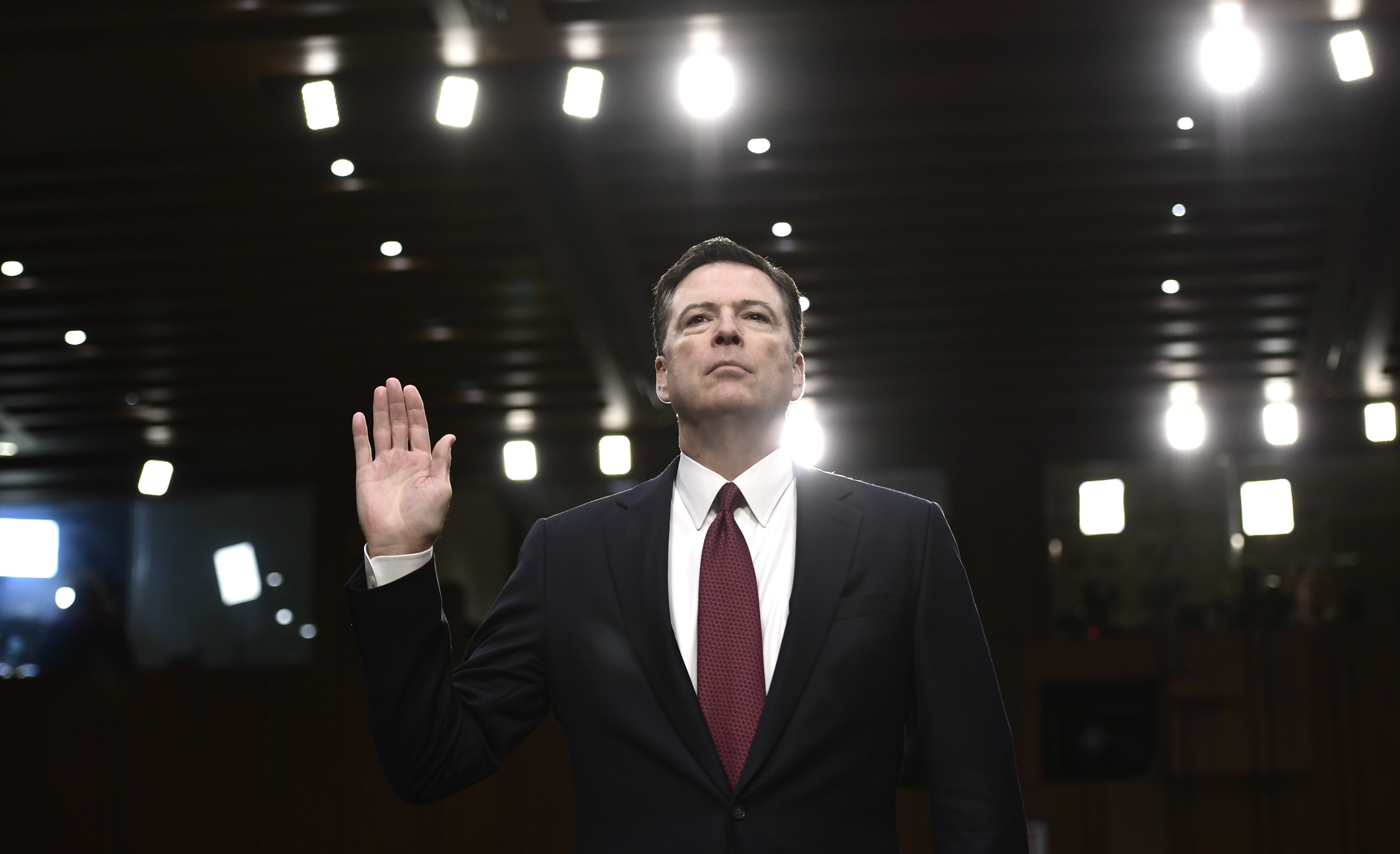 Former FBI Director James Comey takes the oath before testifying to the Senate Intelligence Committee.