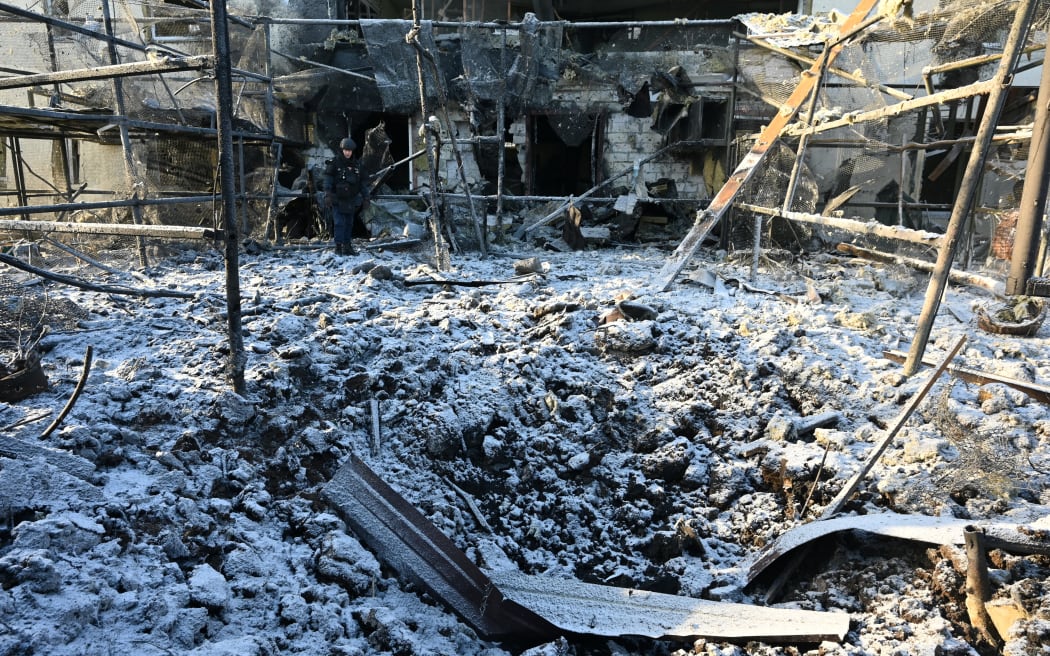 A Ukrainian rescuer works at the site of an airstrike in Kharkiv on January 1, 2026, amid the Russian invasion of Ukraine. (Photo by SERGEY BOBOK / AFP)