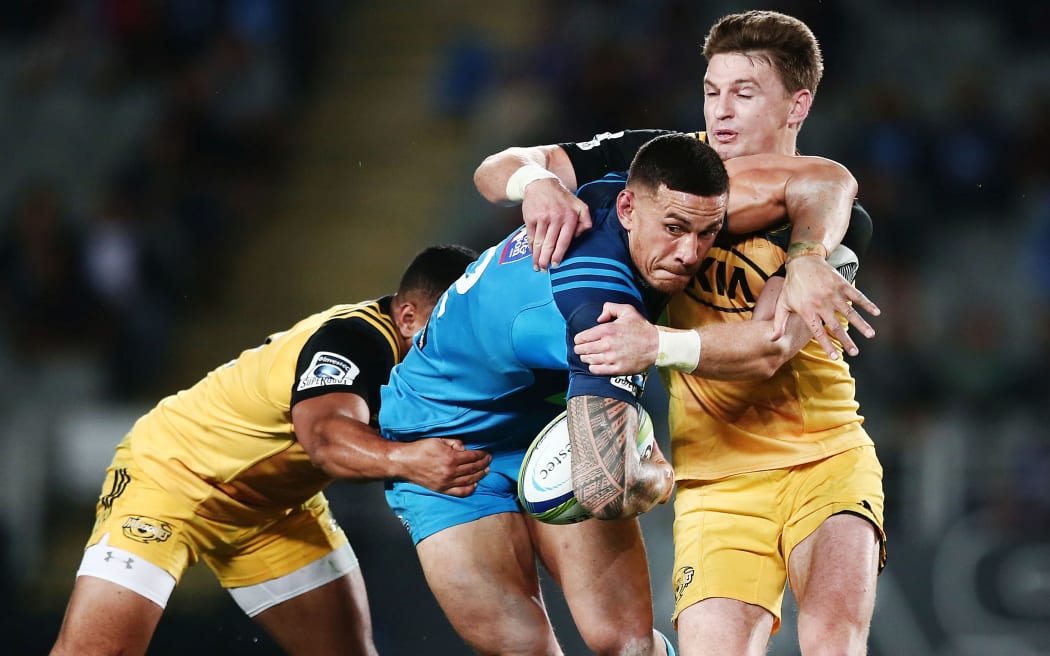 Sonny Bill Williams of the Blues is tackled by Beauden Barrett and Ngani Laumape of the Hurricanes.