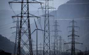 A wind turbine is surrounded by electricity pylons near Evionnaz, Canton of Valais, western Switzerand on March 28, 2022. - (Photo by Fabrice COFFRINI / AFP)