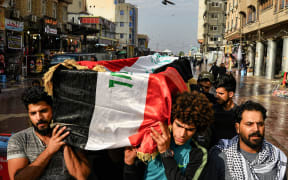 Iraqi mourners carry a coffin, draped in a national flag, of a tuktuk driver who ferried injured protesters and who was later killed in Baghdad.