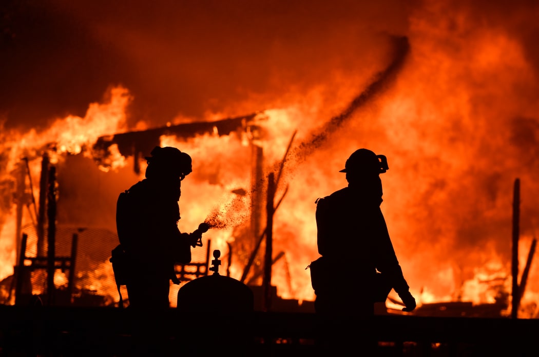 Firefighters douse flames as a home burns in the Napa wine region.