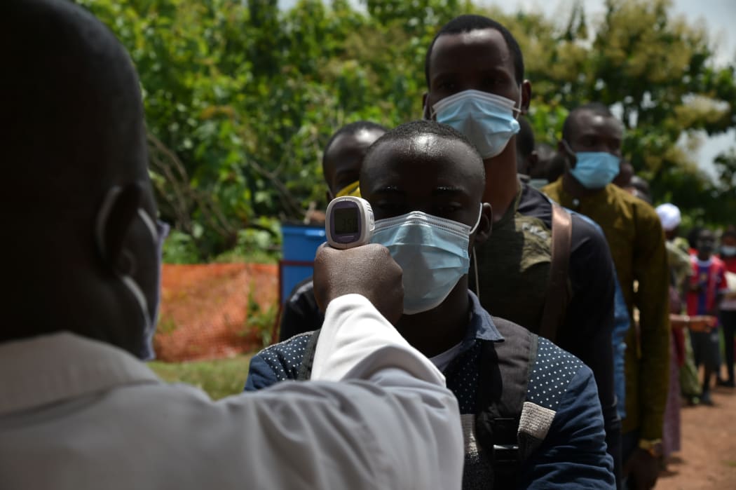 Ivory Coast Ministry of Health workers measures the body temperatures of passengers as a preventive measure against the spread of the COVID-19 coronavirus at a checkpoint at the entrance of Bouaké.
