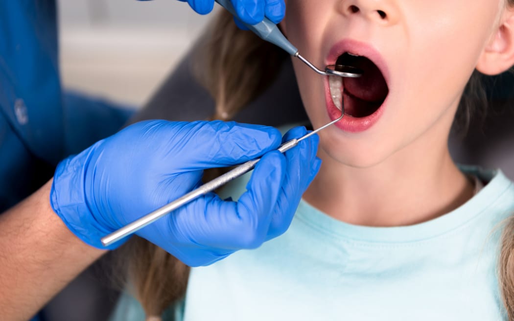 cropped shot of dentist with instruments examining teeth of little child