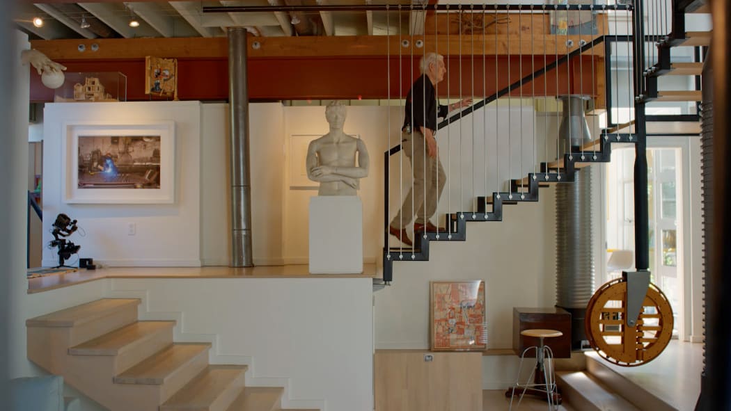 A still from the short documentary film Richard Henriquez: Building Stories featuring the architect Richard Henriquez walking up the stairs in the home he designed for his family.