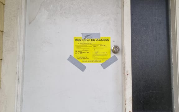 A yellow stickered Māngere house stating residents are only allowed short term entry to the building which has been damaged.
