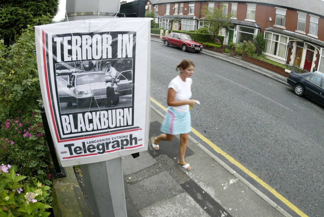 A pedestrian walks past a newspaper front page announcing the arrest of suspects on terrorism charges on Old Preston Road in Blackburn, Lancashire.