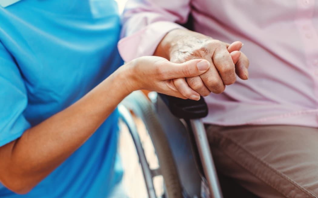 Nurse consoling a senior woman in the nursing home holding her hand in the nursing home