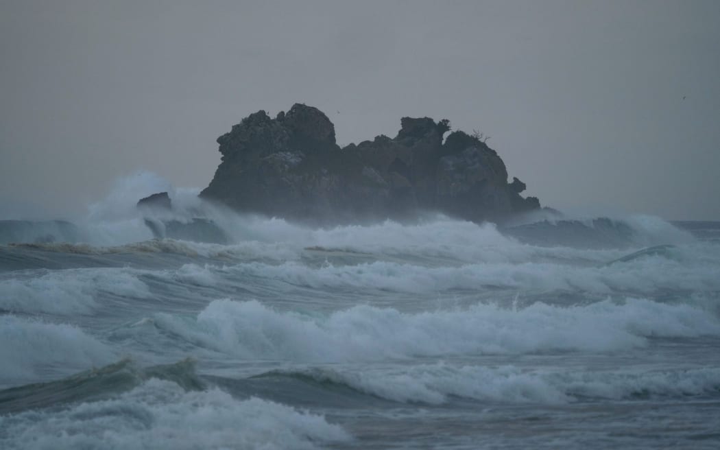 Waves crashing against rock formation island pacific ocean coast sea shore at Opoutere beach Waikato Coromandel Peninsula North Island New Zealand