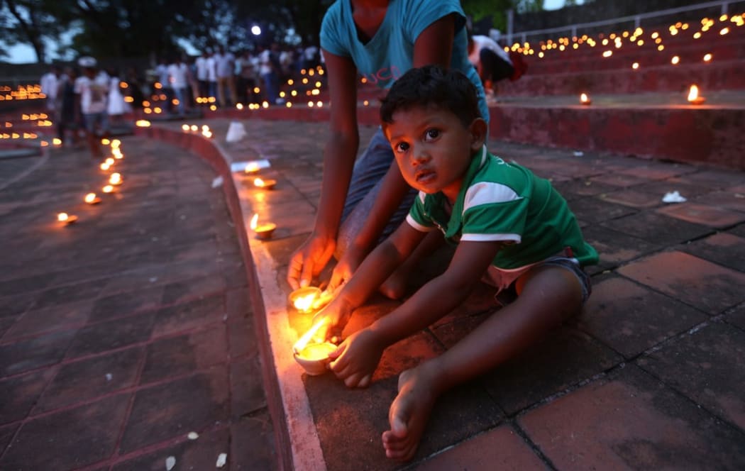 A Sri Lankan child holds a candle during a candlelight vigil, as Sri Lankans  pay tribute to the victims of  the Easter sunday bombings at Colombo, Sri Lanka on 21 June 2019.