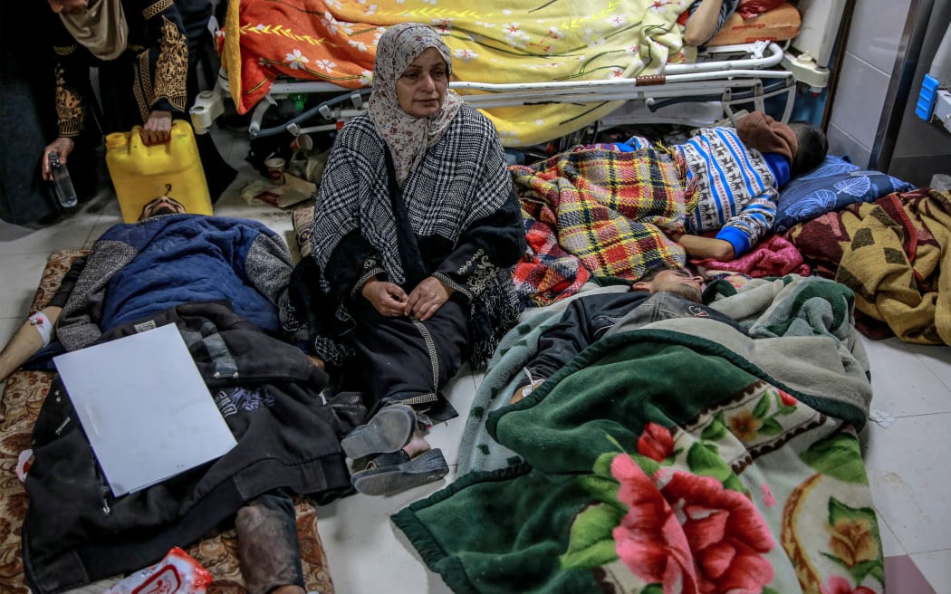 A woman sits among Palestinians at Al-Shifa hospital in Gaza City after they were injured in an early morning incident when residents rushed toward aid trucks in Gaza City on February 29, 2024. The health ministry in Hamas-run Gaza said Israeli forces shot dead dozens of people when a crowd rushed towards aid trucks on February 29. Israeli sources confirmed that troops opened fire at Palestinians, with one saying soldiers thought they "posed a threat", and that many died when they were run over by aid trucks.