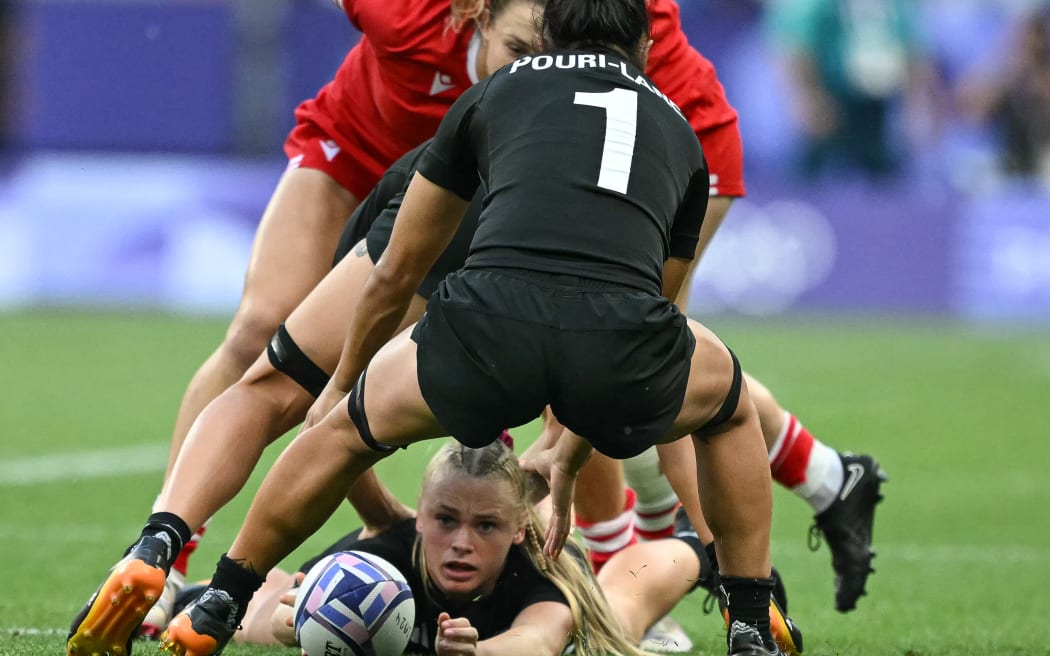 New Zealand's Jorja Miller (C, down) tries to grab the ball during the women's gold medal rugby sevens match between New Zealand and Canada during the Paris 2024 Olympic Games at the Stade de France in Saint-Denis on July 30, 2024. (Photo by CARL DE SOUZA / AFP)