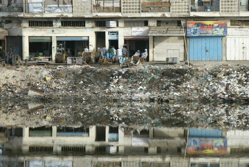Iraqis sit outside their shops on the banks of a canal feeding the Shatt al-Arab river in Basra in May 2003.